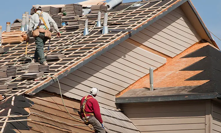Professional roofer repairing shingles on Milwaukee, OR home roof
